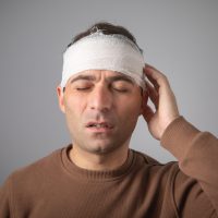 Caucasian man with a bandage on head.
