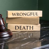 Symbolic representation of wrongful death legal proceedings with a gavel and wooden blocks displaying text