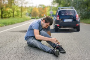 Hit and run concept. Injured man on road in front of a car.
