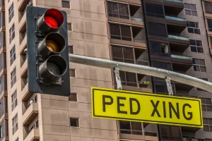 Traffic light with pedestrian crossing sign and a skyscraper background.
